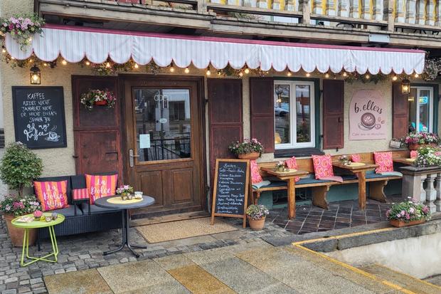 Außenansicht des Cafés b.ellers mit Markise, Lichterkette und Sitzbänken davor