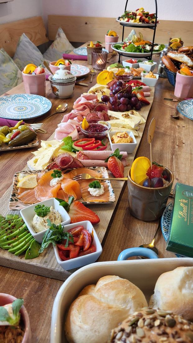 Lange Holztafel mit Lachs, Käse, Aufschnitt, Avocado und frischen Semmeln