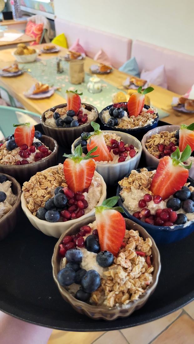 Tablett mit Schälchen Overnight Oats, belegt mit Erdbeere, Heidelbeeren, Granatapfel und Granola